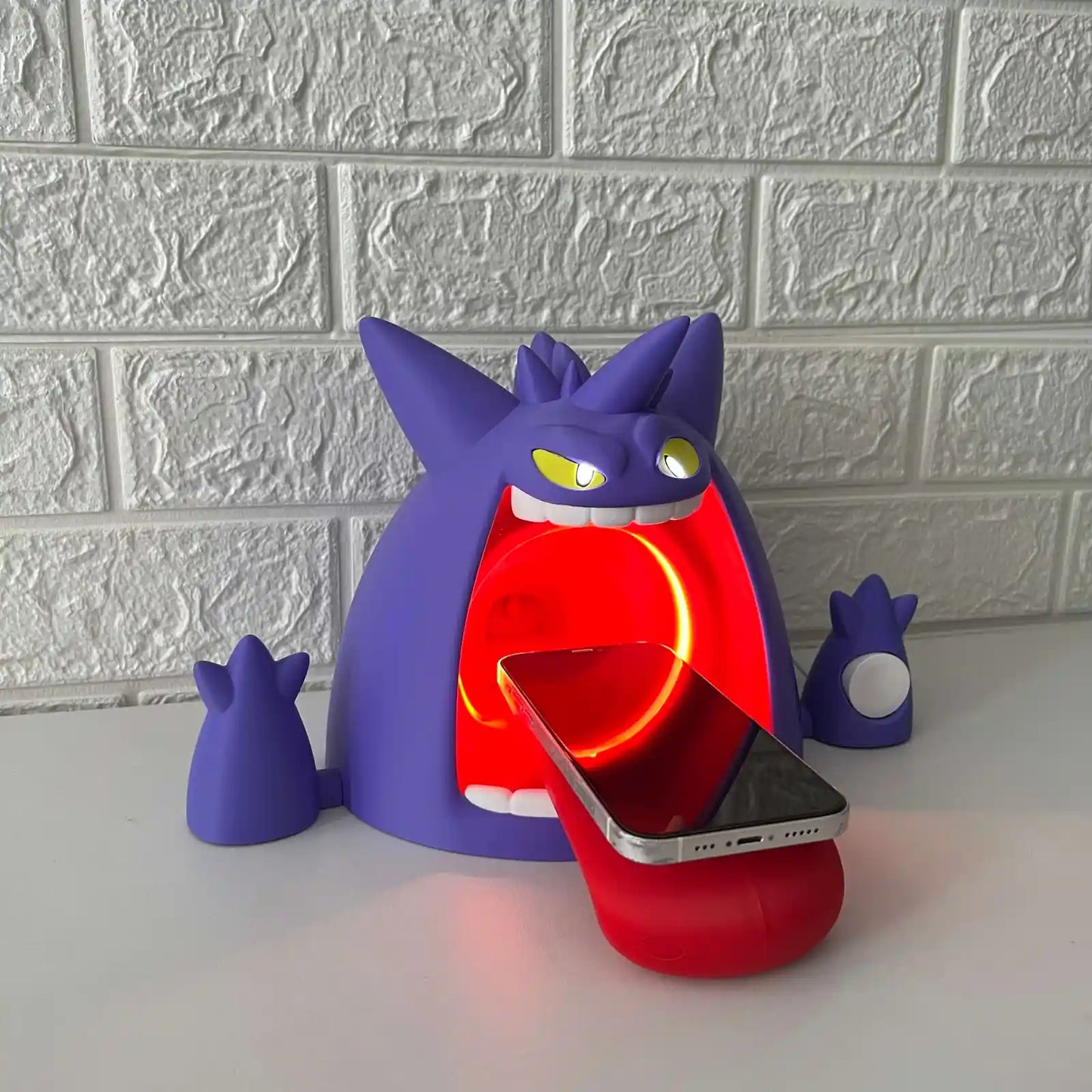 Angled view of Gengar-inspired wireless charger showing phone on stand and bright red LED glow