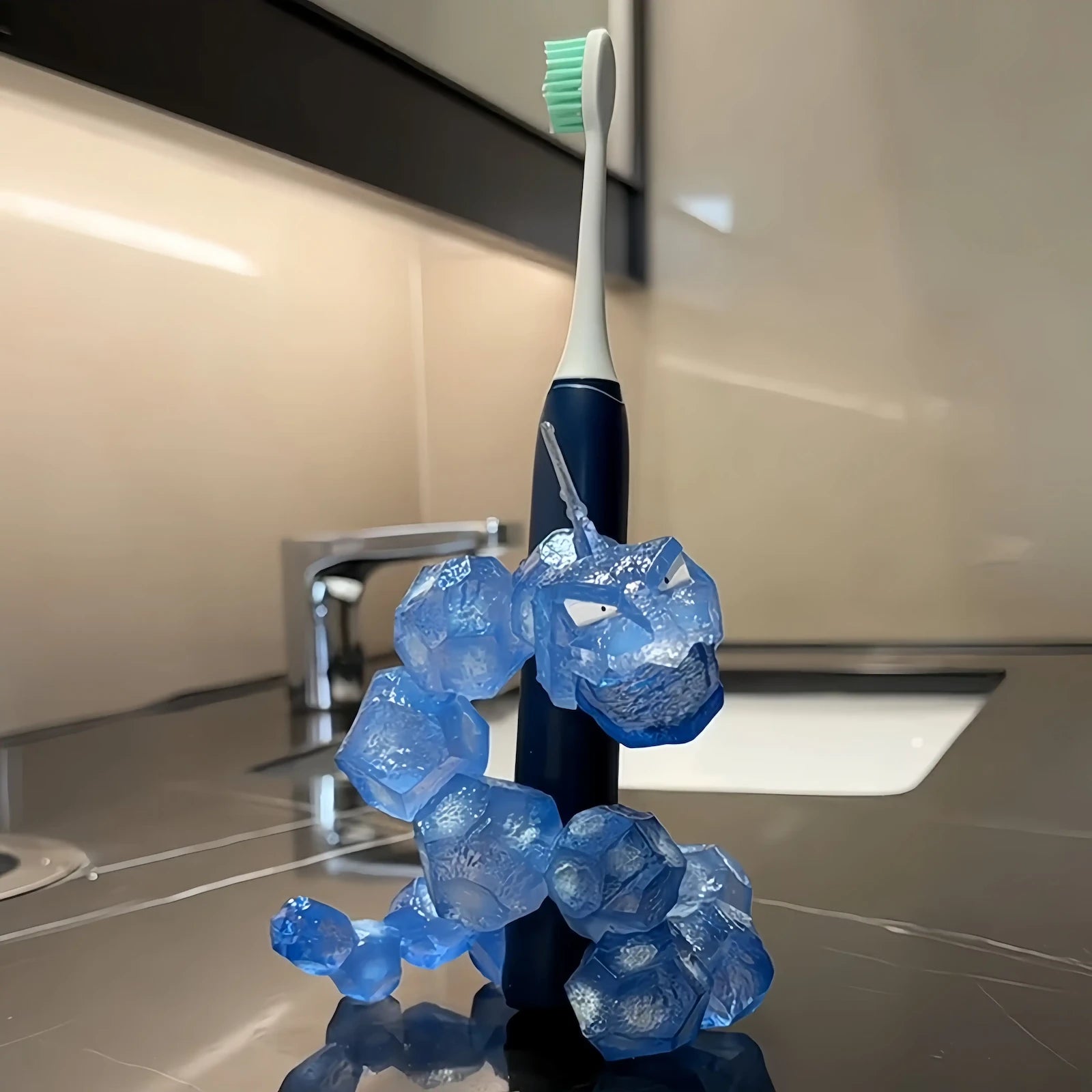 Translucent blue Onix-inspired toothbrush holder standing beside an electric toothbrush on a bathroom vanity